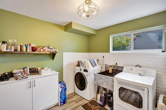 clothes washing area with cabinets, light wood-type flooring, and washing machine and clothes dryer