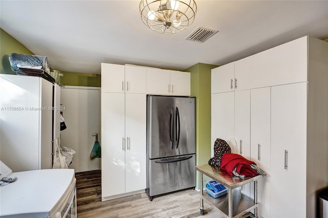 kitchen with stainless steel refrigerator, white cabinetry, and hardwood / wood-style floors