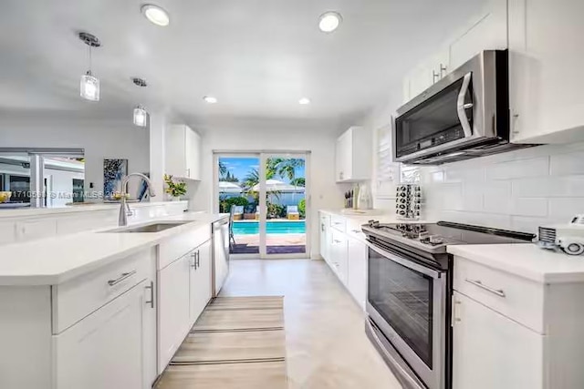 kitchen with white cabinets, appliances with stainless steel finishes, hanging light fixtures, and sink