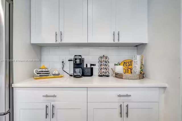 bar featuring white cabinets, tasteful backsplash, and stainless steel refrigerator