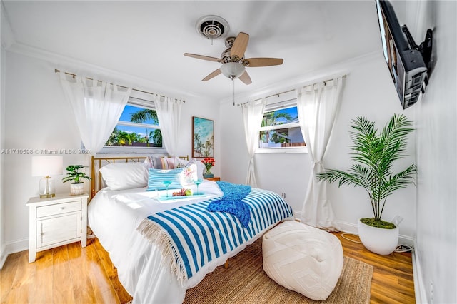 bedroom with light wood-type flooring, ceiling fan, and crown molding