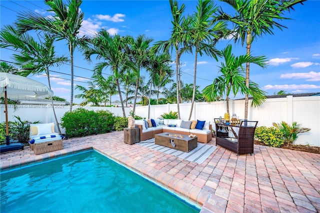 view of swimming pool with a patio area and an outdoor living space with a fire pit