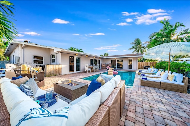 view of swimming pool featuring a patio area and an outdoor living space with a fire pit