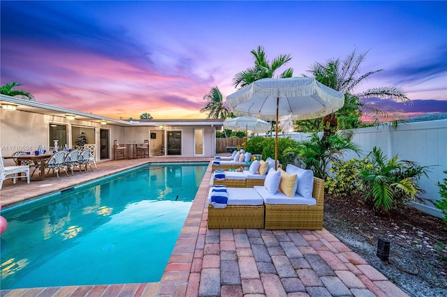 pool at dusk featuring a patio