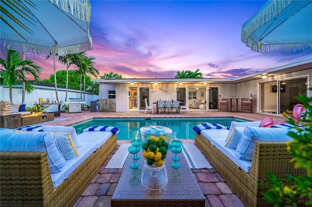 pool at dusk with a patio and an outdoor hangout area