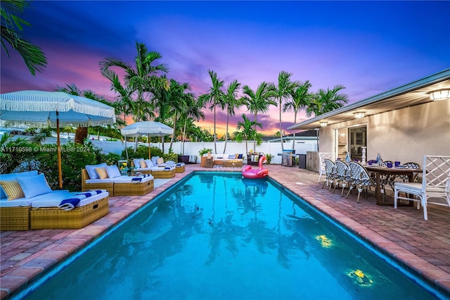 pool at dusk featuring an outdoor hangout area and a patio area