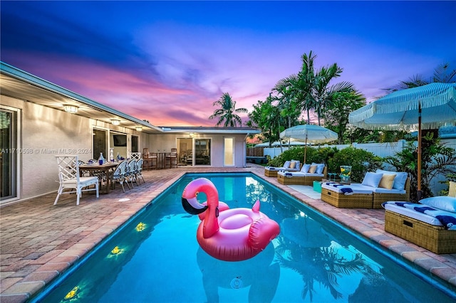 pool at dusk with an outdoor hangout area and a patio area