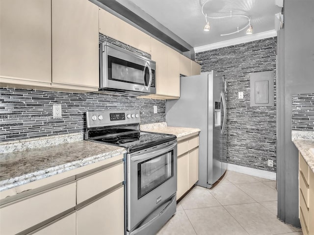 kitchen with stainless steel appliances, crown molding, cream cabinets, decorative backsplash, and light tile patterned flooring