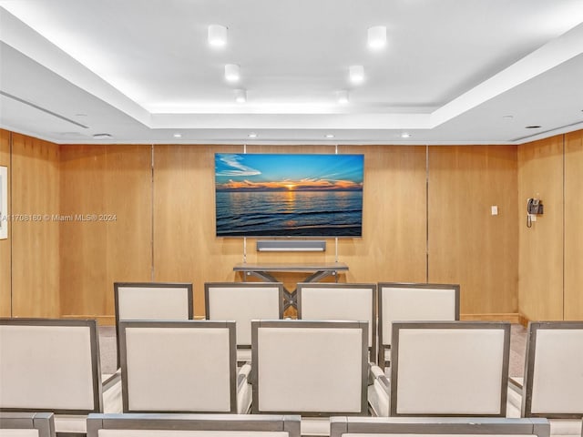 cinema featuring a tray ceiling and wood walls