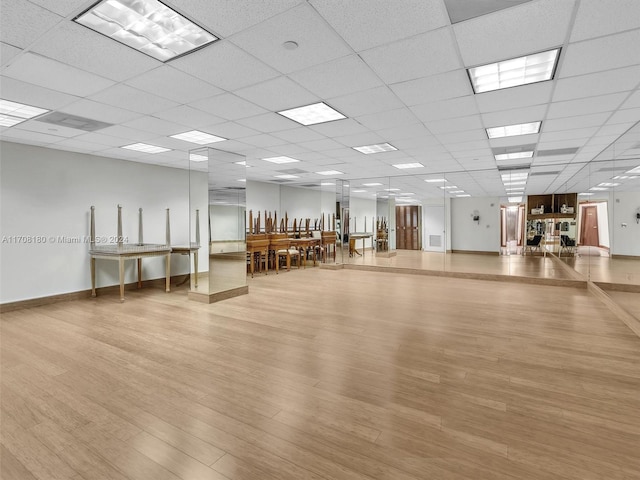 gym with a paneled ceiling and light hardwood / wood-style flooring