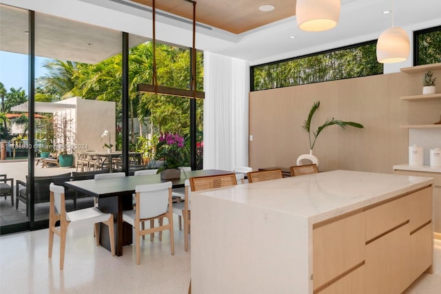 kitchen featuring a kitchen island, light brown cabinets, a wall of windows, and hanging light fixtures