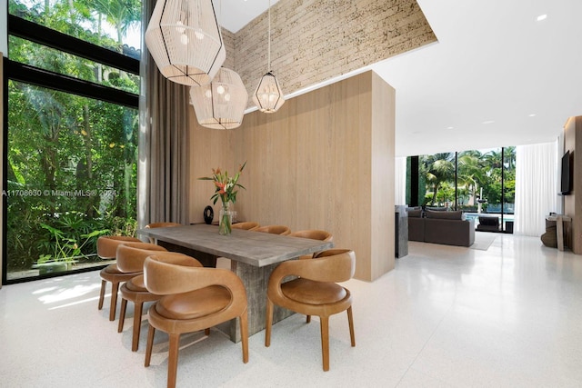 dining space with a high ceiling, expansive windows, and wood walls