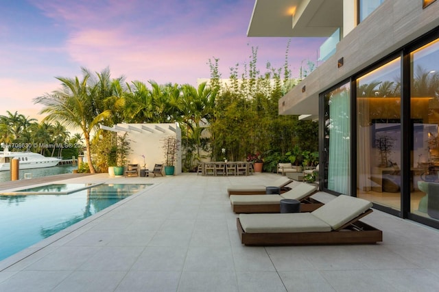 pool at dusk featuring a patio