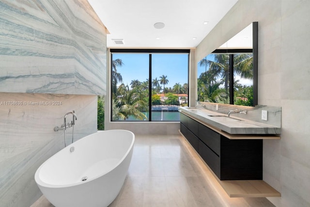 bathroom featuring a wall of windows, a bathtub, and vanity