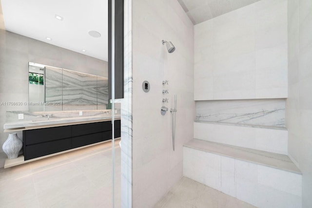 bathroom featuring tiled shower, vanity, and tile walls