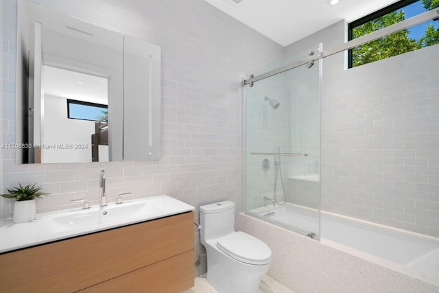 full bathroom with shower / bath combination with glass door, vanity, tasteful backsplash, tile walls, and toilet