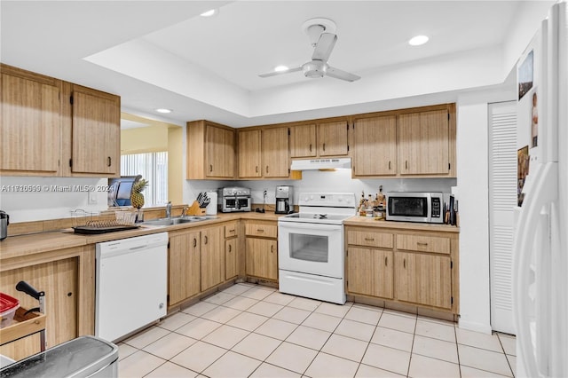 kitchen with white appliances, sink, ceiling fan, light tile patterned floors, and a tray ceiling