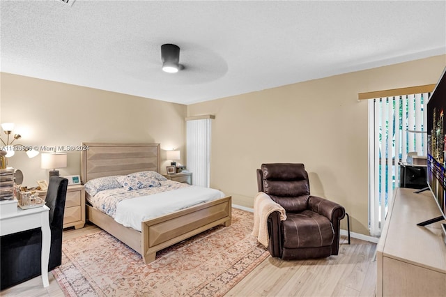 bedroom with ceiling fan, light hardwood / wood-style floors, and a textured ceiling