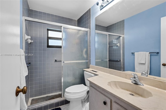 bathroom featuring tile patterned flooring, vanity, a shower with shower door, and toilet