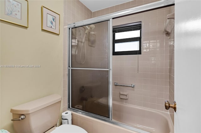 bathroom with combined bath / shower with glass door and toilet