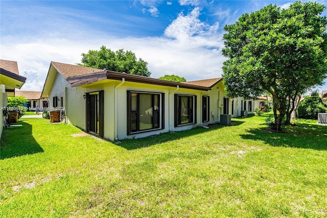 back of property with central AC and a yard