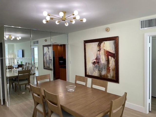 dining area with an inviting chandelier and light hardwood / wood-style flooring