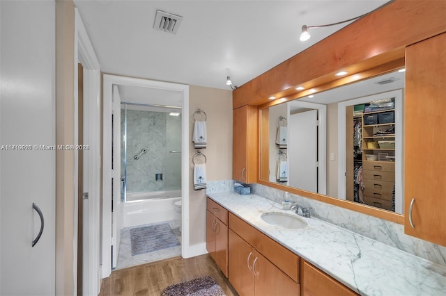 full bathroom with hardwood / wood-style floors, vanity, toilet, and bath / shower combo with glass door