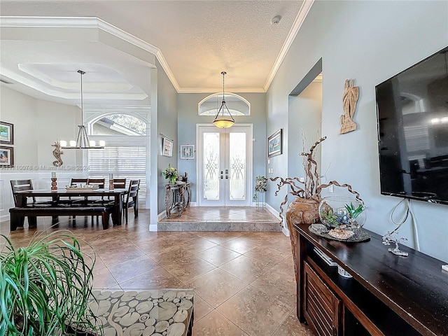 foyer with french doors, a textured ceiling, plenty of natural light, and ornamental molding