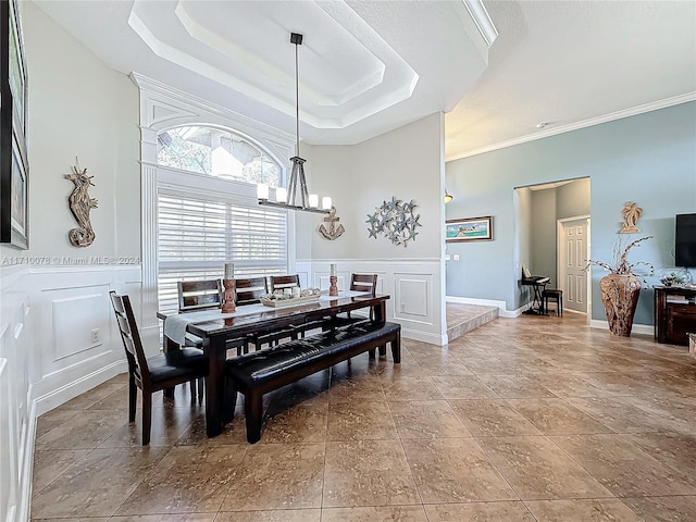 dining space with an inviting chandelier, ornamental molding, and a tray ceiling