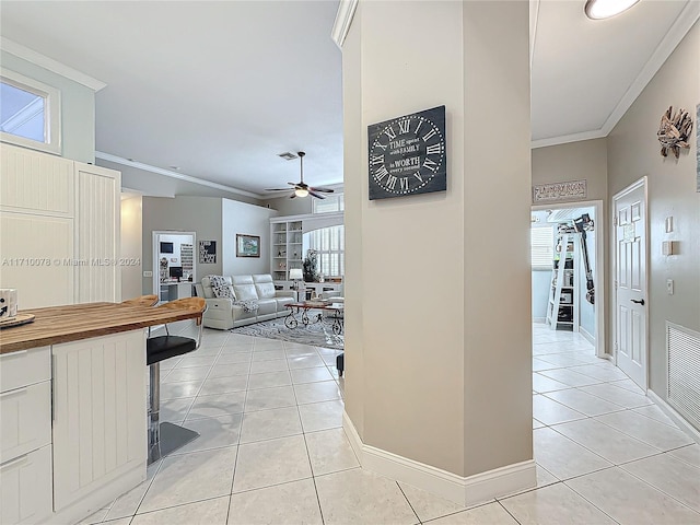 hallway with a healthy amount of sunlight, ornamental molding, and light tile patterned floors