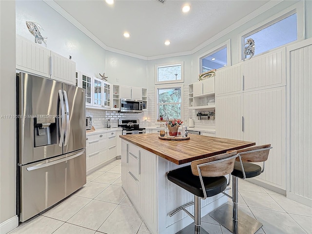 kitchen with a center island, crown molding, appliances with stainless steel finishes, white cabinetry, and a breakfast bar area