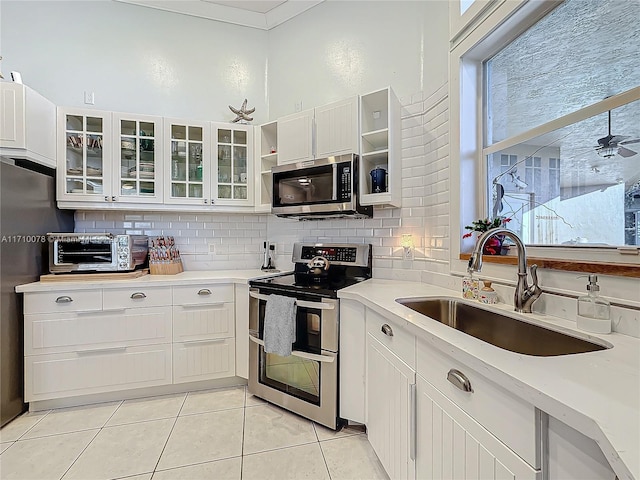 kitchen with light tile patterned floors, white cabinetry, sink, and appliances with stainless steel finishes