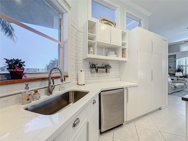 kitchen featuring dishwasher, light stone counters, light tile patterned floors, and sink