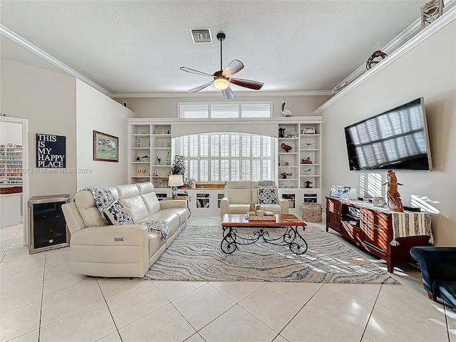 living room with ceiling fan, beverage cooler, a textured ceiling, light tile patterned flooring, and ornamental molding