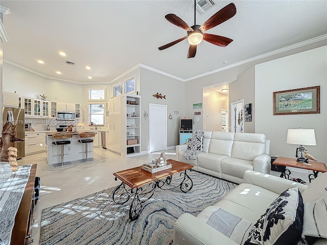 living room with light tile patterned floors, ceiling fan, and ornamental molding