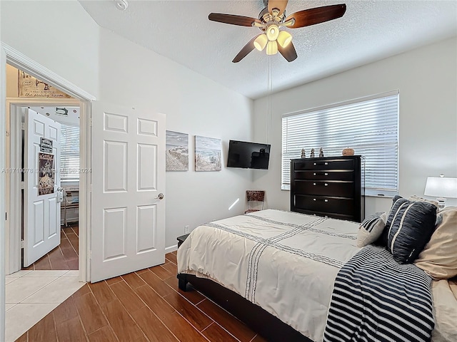 bedroom featuring ceiling fan, wood-type flooring, and a textured ceiling