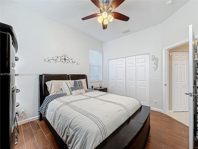 bedroom with hardwood / wood-style floors, a textured ceiling, a closet, and ceiling fan