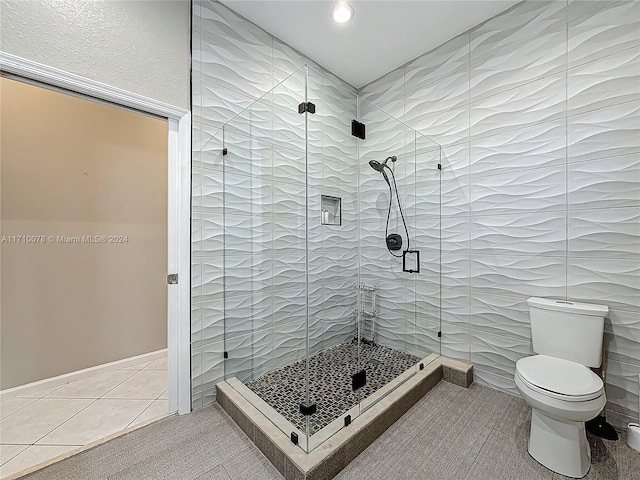 bathroom featuring tile walls, tile patterned flooring, an enclosed shower, and toilet