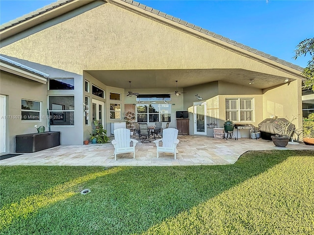 rear view of property with a lawn, a patio area, and ceiling fan