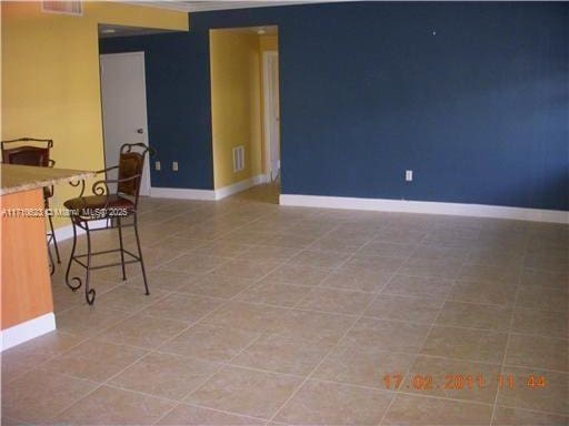 tiled spare room featuring baseboards and visible vents