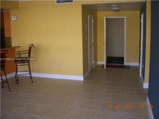 hall featuring baseboards, tile patterned flooring, and visible vents