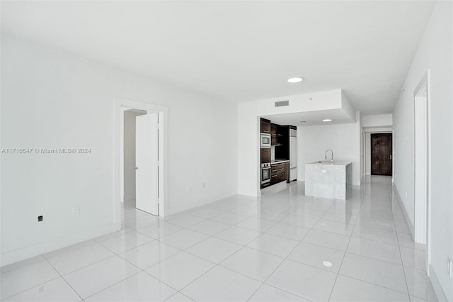 unfurnished living room featuring light tile patterned floors and sink