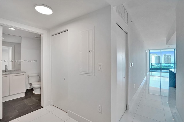 hallway featuring light tile patterned floors, sink, and electric panel