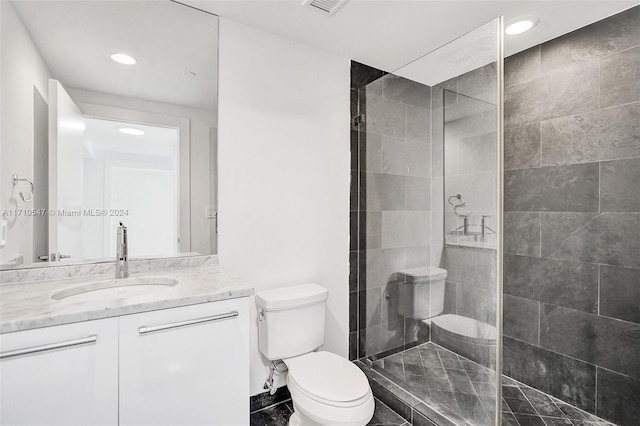 bathroom with toilet, vanity, and tiled shower