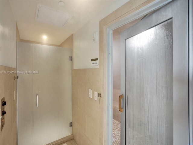 bathroom with a shower with shower door and tile patterned floors