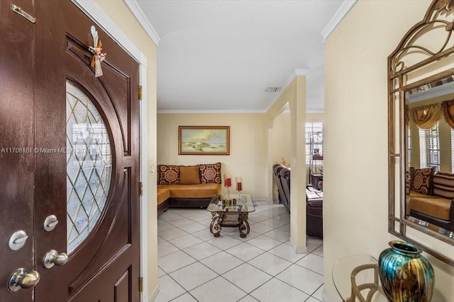 entryway with light tile patterned floors, crown molding, and a wealth of natural light