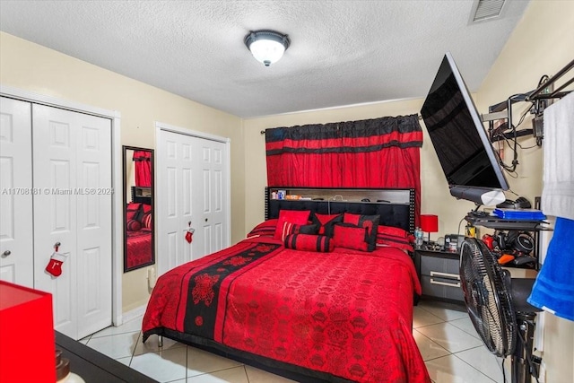 tiled bedroom featuring a textured ceiling and two closets