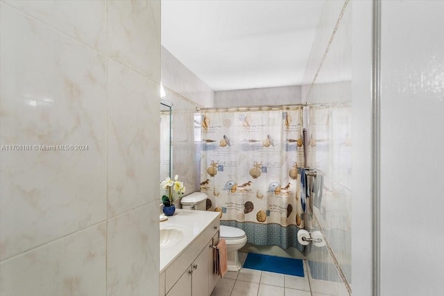 bathroom featuring tile patterned floors, vanity, toilet, and tile walls