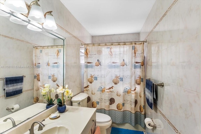 bathroom with vanity, toilet, and tile walls