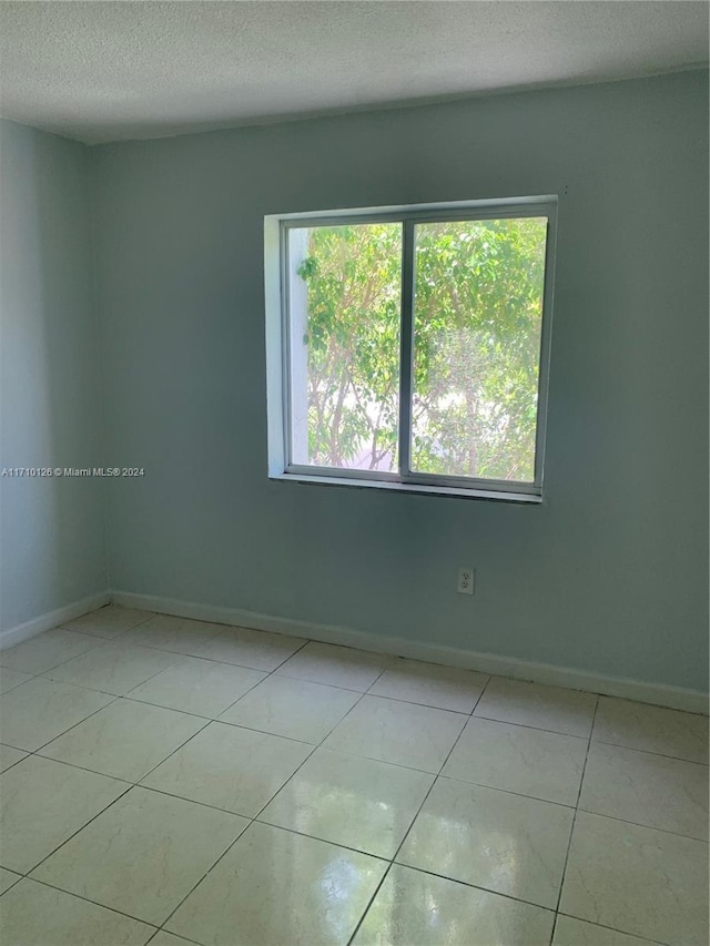 unfurnished room featuring light tile patterned floors and a textured ceiling